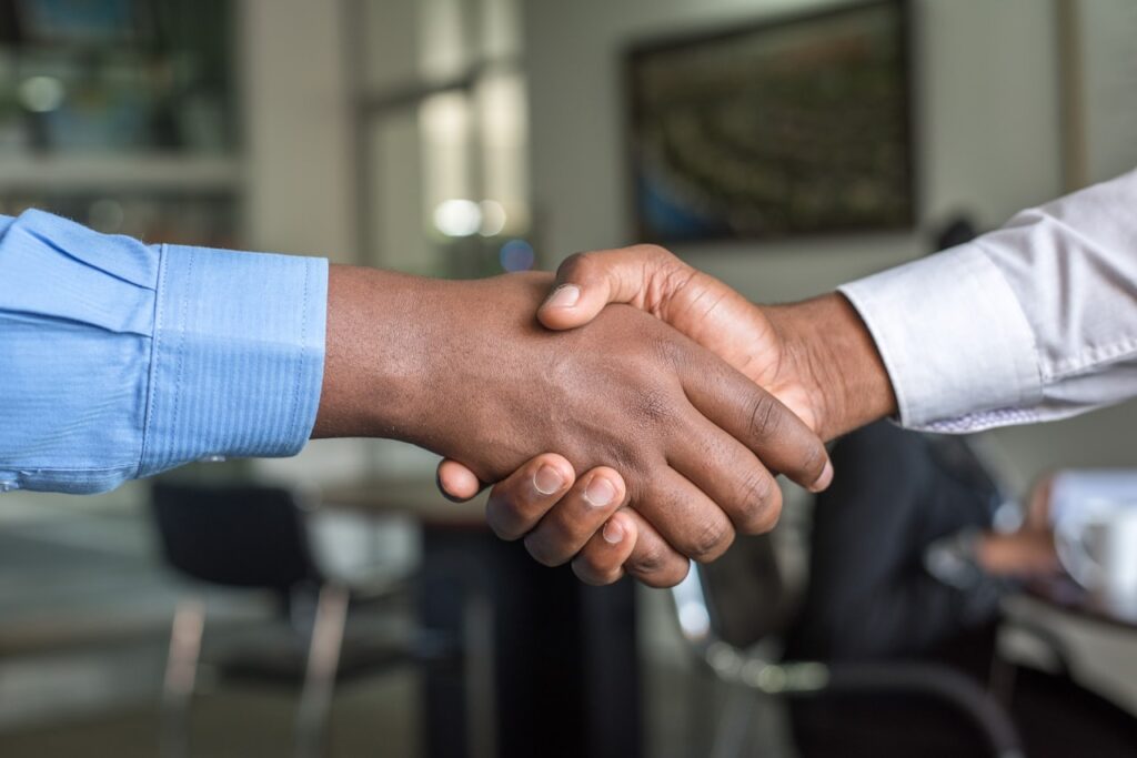 Two people shaking hands in an office, signaling an agreement or partnership.