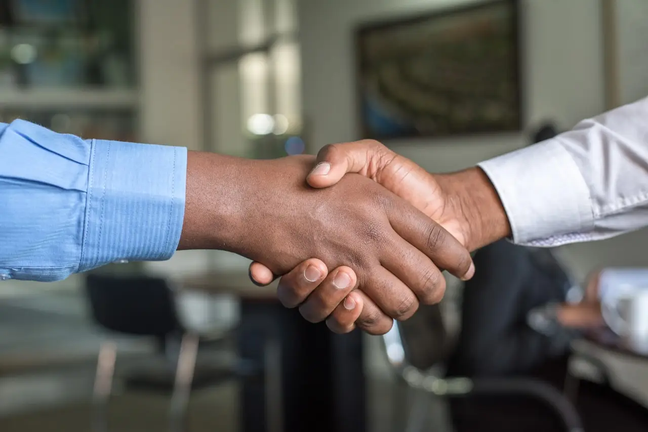 Two people shaking hands in an office, signaling an agreement or partnership.