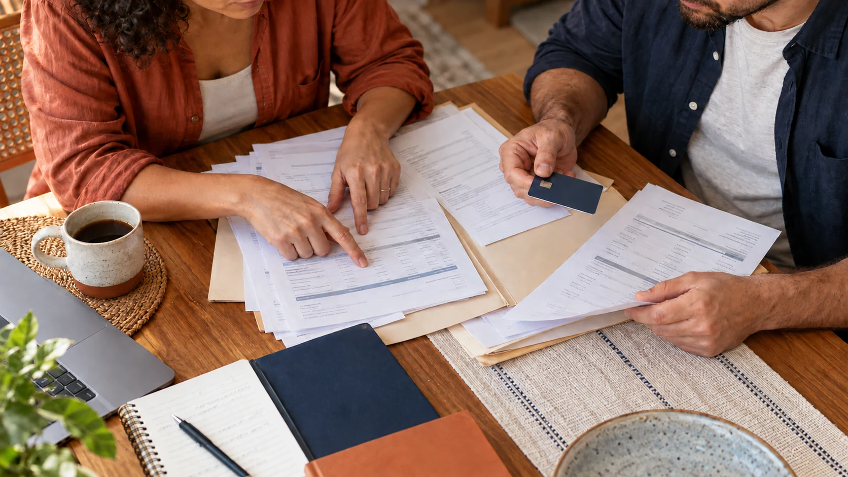 Duas pessoas organizam contratos e extratos antigos para conferir dívidas.
