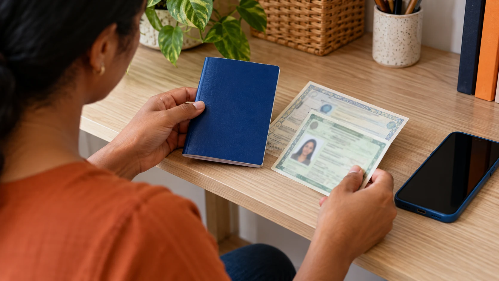 Pessoa compara documentos de cadastro ao lado de um celular.